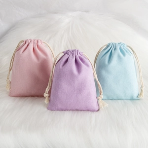 Pink, purple and blue cotton linen drawstring pouches on a soft white plush background