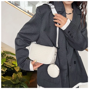 Close-up of a white woven texture crossbody bag with a round coin purse on a model
