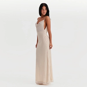 Side view of a beige polka dot backless maxi dress with thin straps and a flowy silhouette