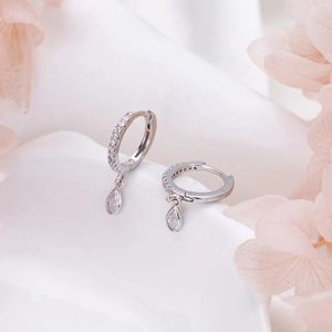 Detail of silver teardrop earrings with pavé crystals on white ceramic tray