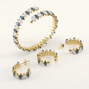 Detail of 18K gold-plated snake bracelet and C-shaped earrings with blue zircon stones