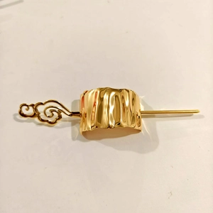 Detailed view of a golden metal hair pin with cloud pattern and textured rectangular ring