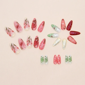 Detailed flat lay of stiletto press on nails featuring hand-painted floral and butterfly patterns