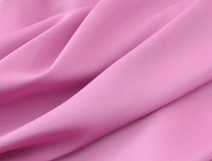 Détail du tissu rose satiné de la robe midi montrant texture soyeuse et drapé élégant