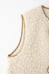 Gros plan sur un gilet en polaire sherpa blanche montrant la texture et les liserés