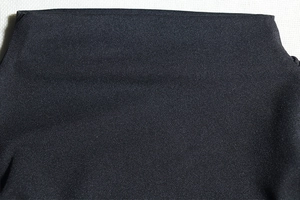 Macro shot of black high-elastic knit fabric showing fine texture and density of the dress
