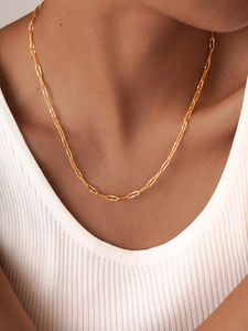 Detail view of a gold faceted paperclip chain necklace worn on a female model