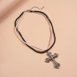 Macro detail of triple-layer necklace featuring pearls and a rhinestone cross pendant