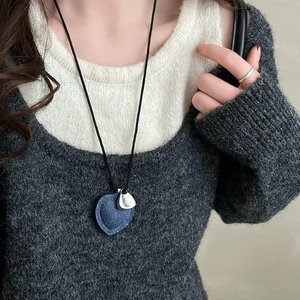 Macro shot of blue denim heart pendant with engraved metal tag on leather woven rope