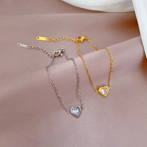 Detailed macro view of heart charm bracelets in gold and silver over pink silk