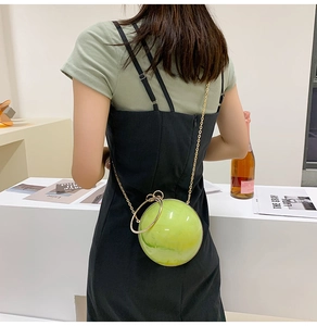 Detailed view of a green marble pattern spherical bag with golden chain and ring handle