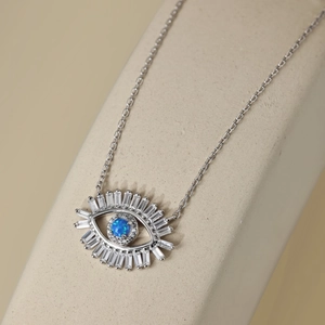 Macro detail of silver Evil Eye pendant with blue stone and white zircon baguettes
