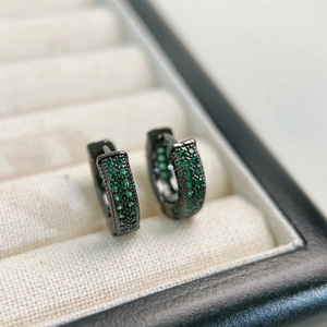 Macro view of gunmetal hoop earrings with emerald green pavé-set cubic zirconia stones