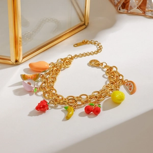 Golden double-layer bracelet featuring diverse enamel fruit charms on a white backdrop