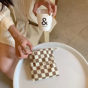 Detailed shot of brown checkerboard knit drawstring bag being held on a white table