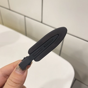Close-up of a black matte hair clip with anti-slip grooves and minimalist duckbill design