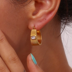 Macro shot of 18K gold plated hoop earring with textured finish and rectangular zircon