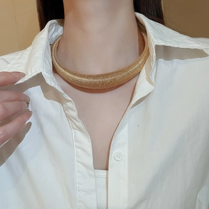 Detailed macro view of a gold-plated chunky choker with horizontal rib texture and metallic shine