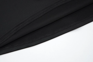Détail d'une robe noire montrant les finitions soignées de l'ourlet à double aiguille