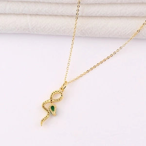 Détail du pendentif serpent doré serti de cristaux et d'une pierre goutte verte