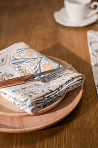 Detail of vintage floral cotton linen napkin on wooden tray with rustic cutlery