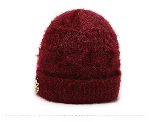 Close-up of wine red knitted winter hat showing fuzzy mohair texture and golden flower detail