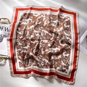 Close-up of paisley pattern silk scarf with orange border and smooth glossy texture
