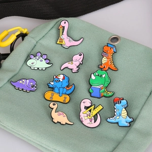 Set of 10 colorful enamel cartoon dinosaur pins attached to a light green canvas bag