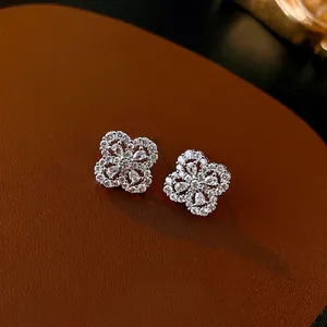 Elegant four-leaf clover stud earrings with pavé zircons on brown leather display