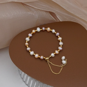 Detail of freshwater pearl bracelet with gold beads on brown leather and satin