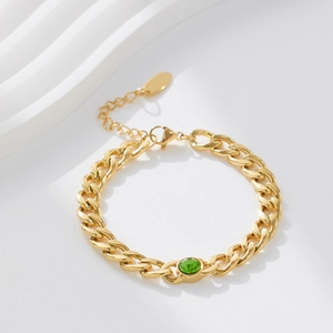 Detail of golden Cuban link bracelet with green oval gemstone and adjustable lobster clasp