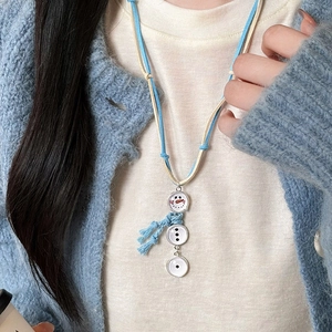 Gros plan d'un pendentif bonhomme de neige avec écharpe bleue sur un pull