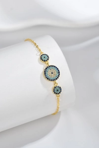 Detail of S925 silver evil eye bracelet with blue stones on a white silk backdrop