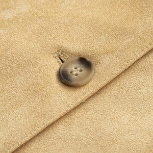 Macro view of light camel faux leather jacket featuring a dark marbled button detail
