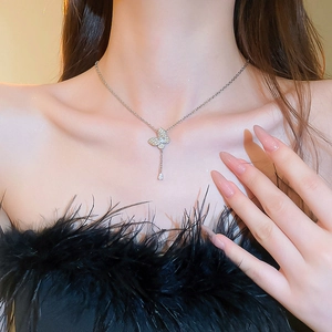 Close-up of a silver butterfly necklace with zircon drop pendant on a woman's collarbone