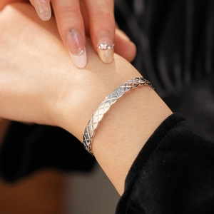 Détail d'un bracelet manchette argenté avec motif croisé et zircon porté au poignet