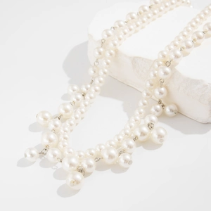 Detail of double-layer faux pearl waist chain with fringe drops on textured stone