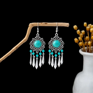 Detail of vintage bohemian earrings with turquoise beads and metallic teardrop tassels