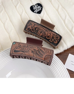 Detail of vintage western poker hair claw clips with leather floral print on knit fabric