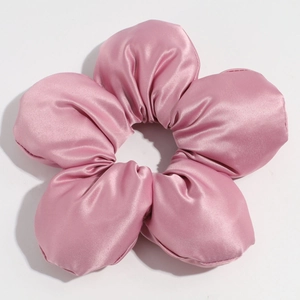 Macro detail of a large fabric flower scrunchie in dusty rose with a silky satin texture