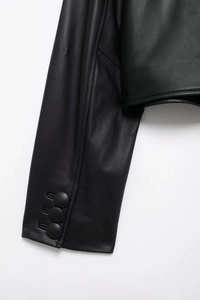 Detail view of black faux leather jacket cuff with three matching round buttons