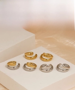 Detail view of thick liquid-style gold and silver open rings on white display stand