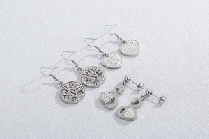 Macro shot of silver stainless steel heart, tree of life, and swan earrings with zircons