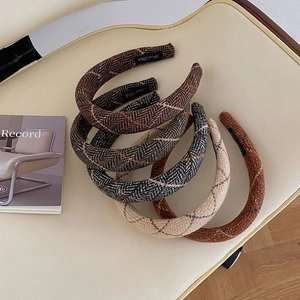 Detailed knit plaid headbands in assorted autumn colors displayed on a beige chair