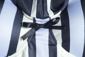 Détail macro des rayures verticales et du nœud en soie noire sur cette robe moulante