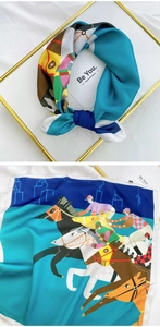 Detail of square silk scarf with horse racing print in teal and navy blue tones