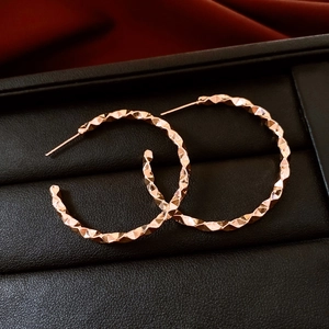 Macro detail of rose gold geometric faceted hoop earrings in a luxury jewelry box