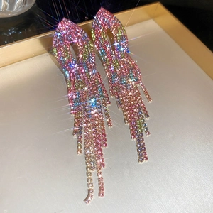 Close-up of elegant gradient rhinestone tassel earrings in a golden jewelry tray