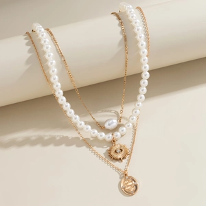 Detailed close-up of triple-layered necklaces with pearls and gold-plated pendants