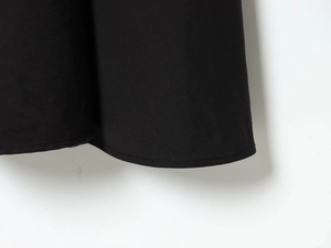 Detailopname van de fijn geplooide zoom en twill-stof van een zwarte blazerjurk voor dames
